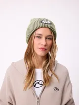 Gorro tipo beanie de tejido acanalado con diseño a rayas verticales en tonos azul y gris. Presenta un parche frontal con el logo de la marca Rusty.