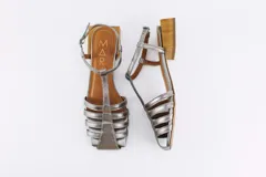 Sandalias plateadas de cuero con tiras finas, punta cuadrada, taco bajo de madera y cierre con hebilla al tobillo.