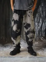 Pantalón unisex de denim con diseño amplio y silueta barrel, inspirado en la bombacha de campo y el pantalón sastrero. Cuenta con lavado irregular efecto tie-dye en tonos negro y gris, pinzas delanteras y bolsillos laterales.