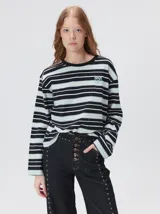 Remera de manga larga con diseño de rayas horizontales en tonos negro, blanco y celeste. Presenta un calce holgado, cuello redondo a la base y logo bordado en el pecho.