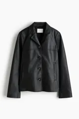 Campera negra de cuero sintético con solapas de muesca, cierre frontal de botones oscuros y bolsillos laterales ribeteados. Presenta costuras de canesú en el frente y en la espalda, y diseño forrado.