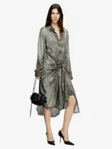 Vestido largo tipo camisa, color gris oscuro con efecto desgastado/decolorado, manga larga y cuello camisero. La prenda se anuda a la altura de la cintura, creando un efecto drapeado asimétrico en la falda.