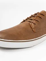 Zapatilla de estilo casual con cordones, confeccionada en cuero sintético color marrón con suela de goma blanca.