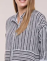 Camisa de rayón con estampado de rayas blanco y negro, de corte fluido, cuello con solapa, cierre frontal con botones y mangas largas regulables.