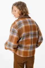 Blazer de corte holgado con diseño a cuadros en tonos naranja, azul y marrón. Presenta solapas anchas de pana en color marrón oscuro, cierre frontal cruzado con dos botones y bolsillos laterales integrados.