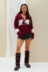 Sweater bordó con cuello alto y cierre frontal parcial, de diseño holgado con franjas blancas en las mangas y una franja blanca ancha en la espalda con la inscripción en letras bordó.