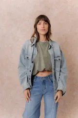 Camisa de jean de calce relajado y lavado claro con efecto vintage. Presenta cuello clásico, cierre frontal con broches metálicos, mangas largas con puños y dos bolsillos con tapa en el frente.
