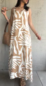 Vestido largo color beige con estampado de hojas blancas, de tirantes finos y corte recto.