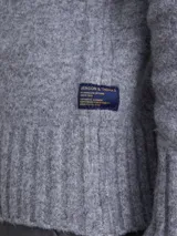 Cardigan de punto gris con cuello tipo chal y cierre frontal de botones. Presenta puños y ruedo acanalados, ofreciendo un diseño clásico y versátil.