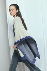 Poncho de tejido de punto en color beige con detalles y bordes en tono azul con diseño de ondas.