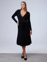 Vestido midi negro de tejido de punto, con escote en V cruzado, mangas largas, lazo en la cintura y apliques de perlas en el escote y la cintura.