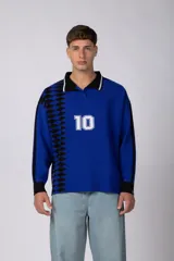 Camiseta de tejido de punto con cuello polo, manga larga y diseño inspirado en camisetas de fútbol retro. Presenta un color azul vibrante con un patrón geométrico lateral en negro y el número 10 estampado en el frente.