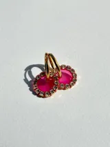 Aros de acero quirúrgico con dije circular de resina rosa y borde de strass dorados.