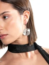 Caravanas de diseño colgante con argolla y dije metálico en forma de flor texturizada.