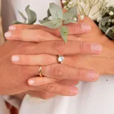 Anillo solitario de oro blanco 18k con una piedra central de aguamarina en corte ovalado y pequeños brillantes laterales engarzados en cuatro puntas.