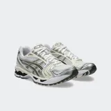 Championes de running Asics modelo Gel Kayano 14, con diseño retro inspirado en los años 2000. Presentan una estructura de malla técnica con superposiciones metálicas plateadas y detalles en gris oscuro, incorporando tecnología GEL en la suela para una amortiguación superior.