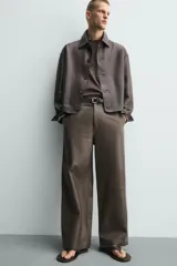 Pantalón de corte balloon fit confeccionado en piel, con bolsillos delanteros y traseros de vivo, cierre frontal con cremallera y botón.