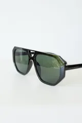 Lentes de sol con armazón de policarbonato negro y cristales tonalidad ámbar, con diseño de puente doble estilo aviador.