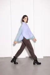 Camisa corta con cuerpo a rayas verticales azules y blancas, mangas a rayas verticales verdes y blancas, cuello camisero y cierre frontal con botones dorados.