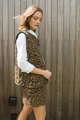 Chaleco reversible con diseño acolchado, presenta un lado con estampado animal print de leopardo y el otro lado en corderito negro. Cuenta con cierre frontal de botones y bolsillos frontales aplicados.