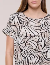 Blusa de silueta holgada y recta, confeccionada en crepe de poliéster con estampado animal print. Presenta escote redondo clásico, mangas cortas de hombro caído con puño doblado y ruedo ligeramente curvo.