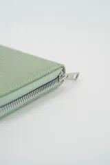 Billetera cuadrada de color verde menta con textura de efecto piel de reptil y cierre perimetral metálico.