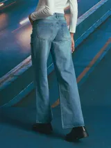 Jean de corte recto y tiro medio, confeccionado en denim de tono azul medio con costuras en contraste. Presenta diseño de cinco bolsillos y cierre frontal con botón metálico.