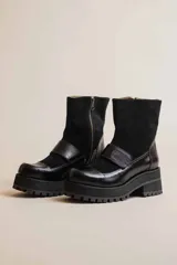 Botas negras de cuero con caña media, plataforma y hebilla decorativa.