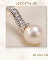 Caravanas colgantes de plata con diseño curvo adornado con circonias y rematadas con una perla blanca.