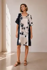 Vestido midi de corte recto y holgado, con mangas cortas y cuello redondo. Presenta un diseño estampado con bloques de color y motivos florales en tonos azul marino y crudo.