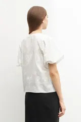 Blusa amarilla con estampado floral, mangas cortas abullonadas y cuello redondo.
