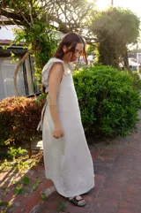 Vestido largo color cemento confeccionado en lino 100%, con terminación en overlock color chocolate y espalda regulable.