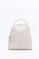 Mochila color beige en símil cuero texturizado, con líneas limpias y formato compacto. Cuenta con doble compartimento principal con cierre metálico, bolsillos laterales y manija superior.