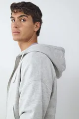 Buzo de algodón gris melange con capucha ajustable mediante cordones, cierre frontal de cremallera y puños y ruedo acanalados.