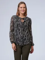 Blusa de gasa estampada en blanco y negro, marca Tahari. Tiene cuello redondo con escote en V y lazo, mangas largas con puño elastizado y forro a tono.