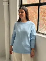 Sweater de punto color celeste con diseño de rombos en relieve en el frente, cuello redondo y mangas largas con puños ajustados.