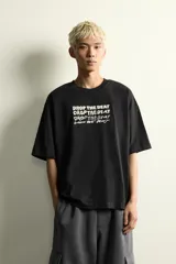 Camiseta de corte relajado color negro, con cuello redondo y manga corta. Presenta bordados a contraste en el frente con la frase 'Drop the beat' repetida en diferentes estilos tipográficos.