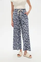Pantalón de algodón estampado con diseño botánico de hojas en tonos verdes sobre base blanca, de corte holgado, tiro medio y cintura elástica con cordón de ajuste ajustable.