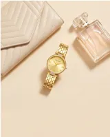 Reloj analógico de mujer con caja redonda y malla de eslabones metálicos, acabado en tono dorado. Presenta una esfera minimalista con marcadores de hora y detalles brillantes.