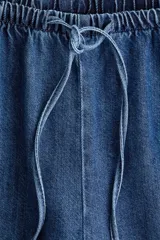 Pantalón denim de corte holgado en mezcla de lyocell y algodón, color azul. Presenta tiro alto con cintura elástica revestida y cordón ajustable, bolsillos laterales discretos y piernas rectas.
