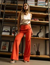 Pantalón naranja de crepe elastizado, corte recto, con bolsillos delanteros y apliques de botones metálicos.