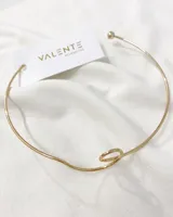 Gargantilla rígida dorada con terminaciones redondeadas y detalle de nudo en el centro.