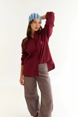 Camisa de corte oversize color bordó, con cuello camisero, mangas largas y bordado en hilo rojo en la espalda con la frase The Winter League. Presenta recortes con costuras a contratono y detalle de placa metálica pequeña en la parte superior trasera.