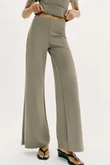 Pantalón largo negro de tiro alto, confeccionado en tejido elástico, con cintura elástica y diseño de pierna ancha tipo palazzo con bajo evasé.