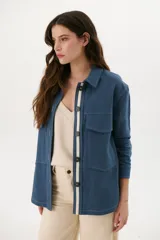 Sobrecamisa azul con cuello clásico, cierre frontal con botones y bolsillos de parche en el pecho.