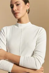 Polera de manga larga color blanco, con cuello alto y costura vertical decorativa en el frente.