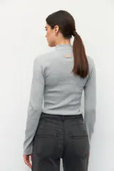 Polera de tejido de punto acanalado en color crema, con cuello alto y manga larga, de ajuste ceñido al cuerpo.