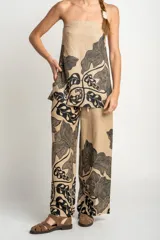 Pantalón de lino color beige con estampado de hojas negras, corte flare y tiro alto.