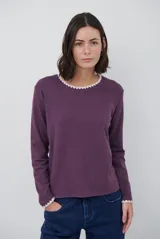 Remera de manga larga en color azul marino, confeccionada en tejido suave. Presenta un delicado detalle de bordado festoneado en color blanco tanto en el cuello redondo como en los puños, aportando un toque distintivo a esta prenda básica.