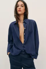 Camisa de corte amplio confeccionada en algodón, con cuello solapa, manga larga, bolsillo delantero de plastrón y cierre frontal con botones.